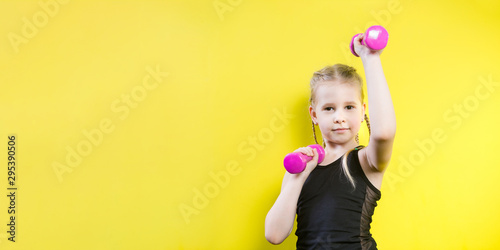 Theme sport and health. Beautiful caucasian child girl with pigtails posing on yellow background with smile. little athlete holding pink dumbbells. Banner for advertising  space for text copy space