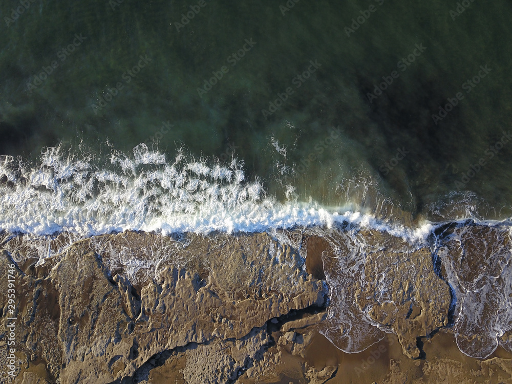 Aerial photograph of a rocky coastline with arriving and breaking ocean waves in Bilbao Spain