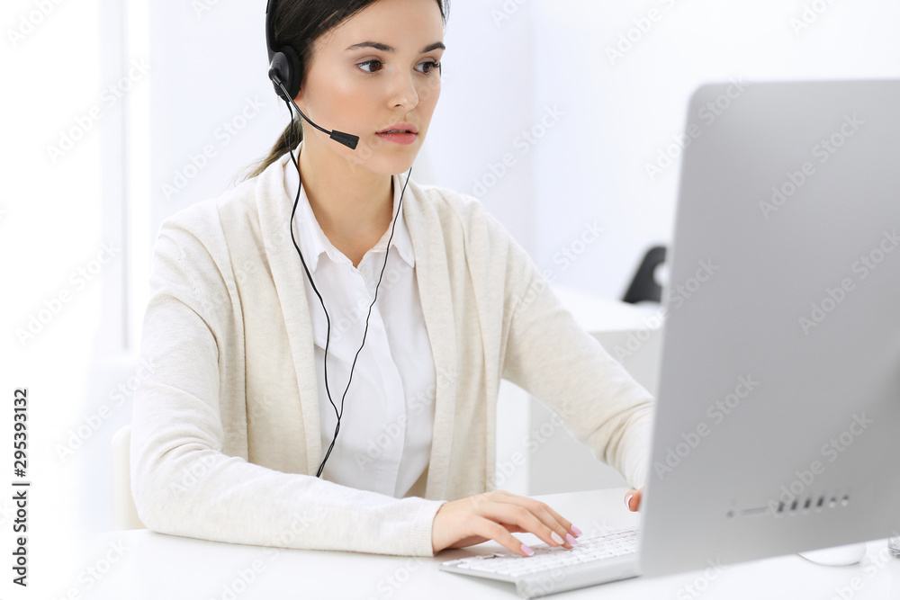 Call center. Beautiful woman receptionist sitting in headset at customer service office. Group of operators at work. Business concept Call center. Beautiful woman receptionist sitting in headset at customer service office. Group of operators at work. Business concept