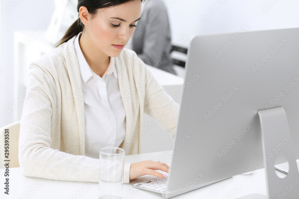 Business woman working with computer in office, female colleague at background. Headshot of Lawyer or accountant at work while sitting at the desk Business woman working with computer in office, female colleague at background. Headshot of Lawyer or accountant at work while sitting at the desk