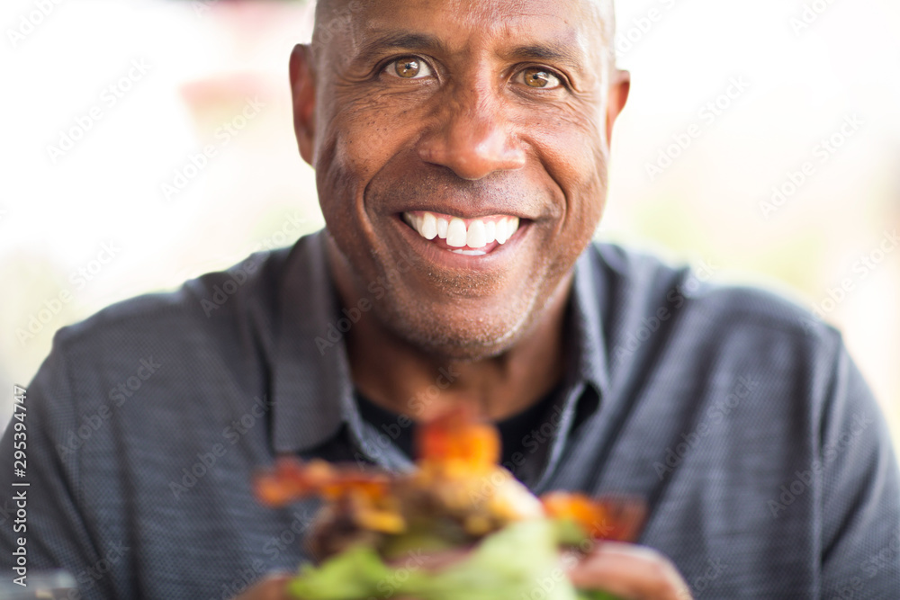 African American man eating a burger without a bun. African American man eating a burger without a bun.