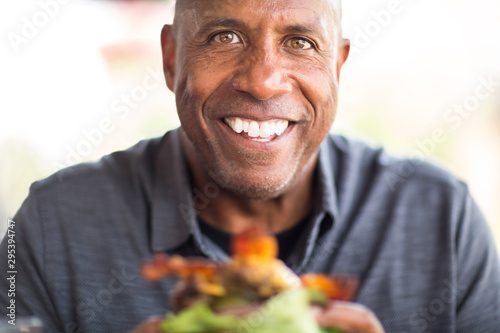 African American man eating a burger without a bun.