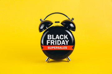 Black Friday concept. Alarm clock on yellow background.