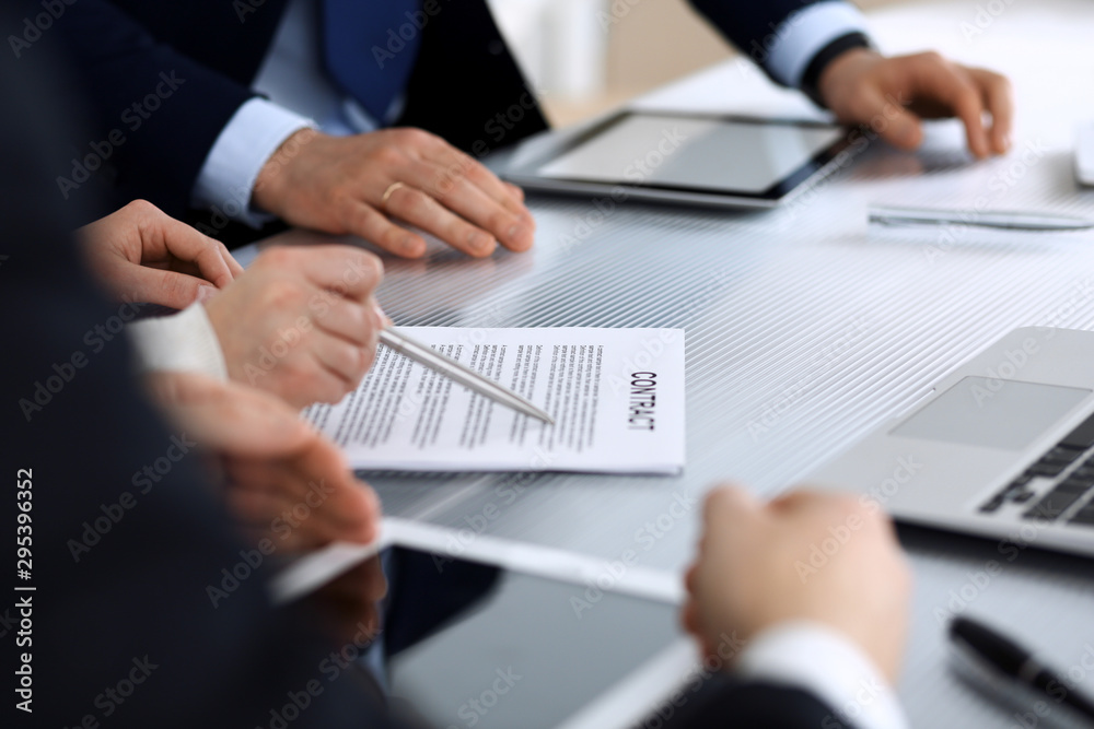 Business people discussing contract working together at meeting at the glass desk in modern office. Unknown businessman and woman with colleagues or lawyers at negotiation. Teamwork and partnership
