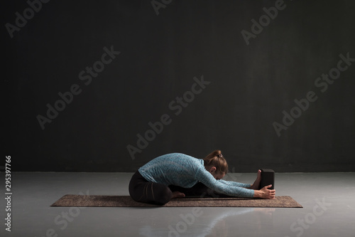 Woman doing yoga training, sitting in Janu Sirsasana, head to knee forward bend pose, asana for stretching shoulders, spine. Studio shot photo