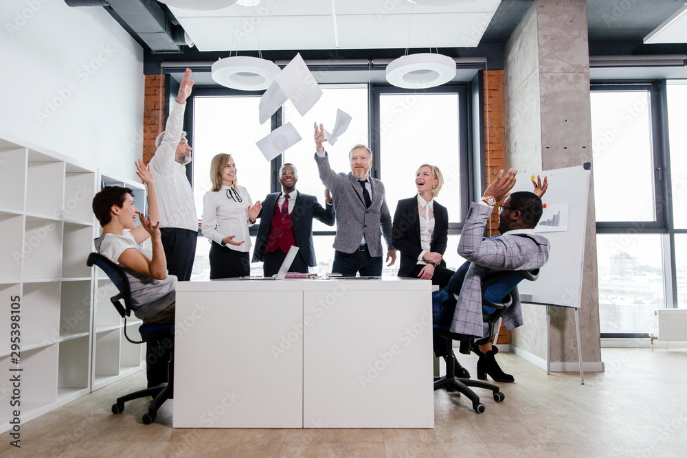 Business people of different ages enjoyed the success of standing at the table, tossing slips of paper Business people of different ages enjoyed the success of standing at the table, tossing slips of paper