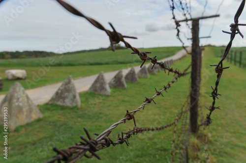 Detail of a barbed wire fence and blurred concrete obstacles in background