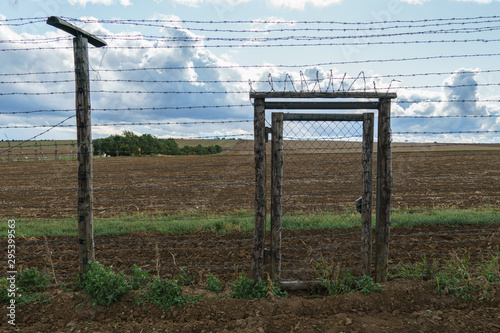 Barbed wire fence with gate and look in the field - no way to escape