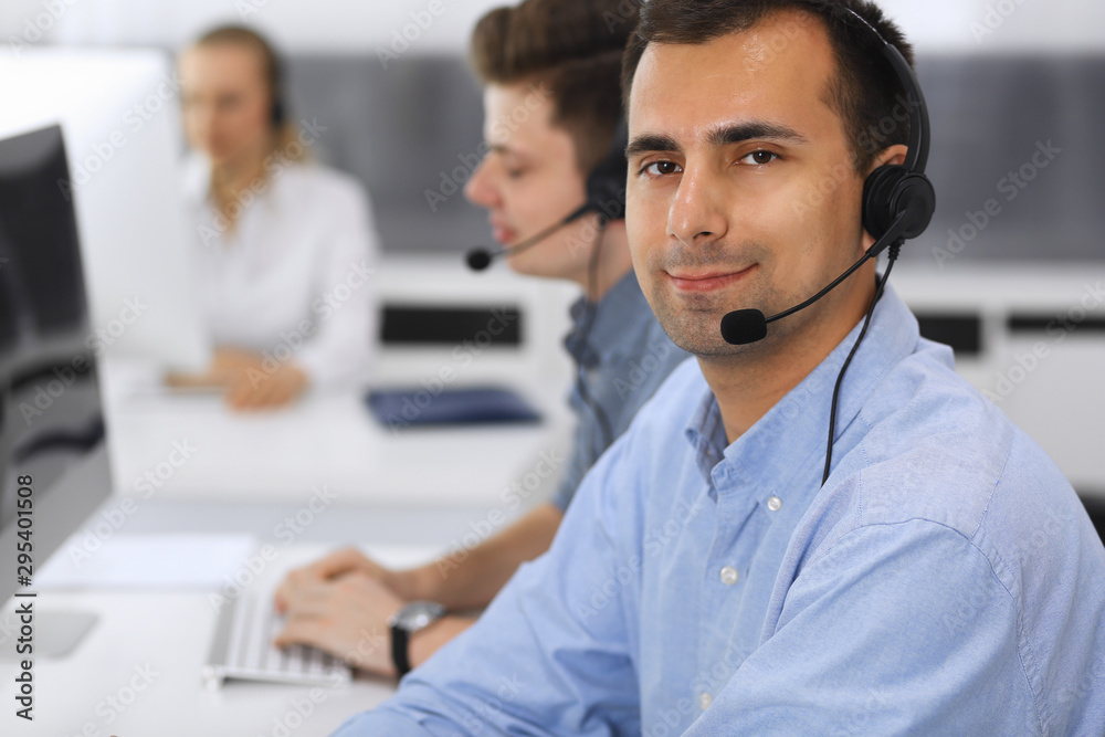 Call center. Group of casual dressed operators at work. Focus on adult businessman in headset at customer service office. Telesales in business Call center. Group of casual dressed operators at work. Focus on adult businessman in headset at customer service office. Telesales in business