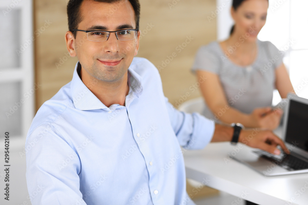 Businessman and hispanic businesswoman using tablet computer in modern office. Headshot of entrepreneur at meeting. Group of diverse people. Teamwork, partnership and business concept