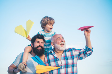 Young boy with father and grandfather enjoying together in park on blue sky background. Grandfather playtime. Happy three generations of men have fun and smiling on blue sky background.