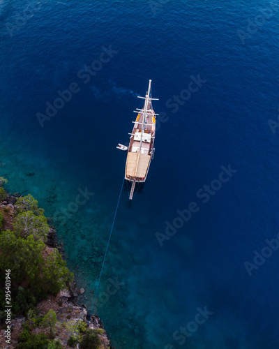 Traditional Turkish Gulets along the mountainous mediterranean coastline at sunset. The luxury boats dock against the cliffs for the night for shelter from the winds. Aerial drone shot from above. 