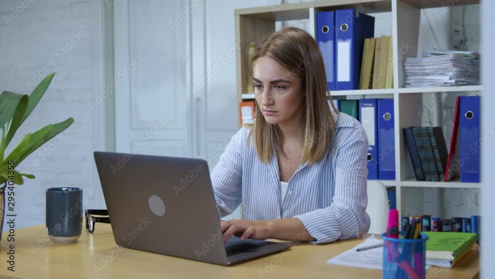 Attractive young woman typing laptop keyboard working on corporate computer in modern office. Portrait of smart girl using notebook at work. Attractive young woman typing laptop keyboard working on corporate computer in modern office. Portrait of smart girl using notebook at work.
