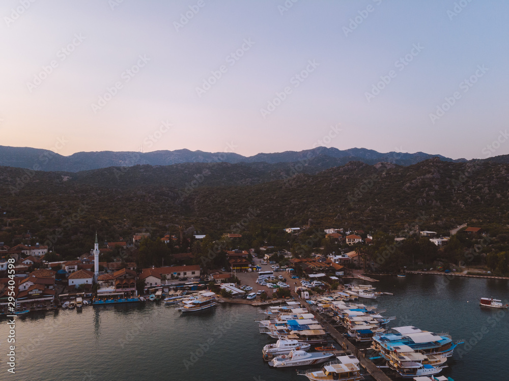 The sun setting over a quiet bay near Fethiye, Turkey. The traditional Turkish gulets line the shore with the mountainous coastal landscape in the background. 