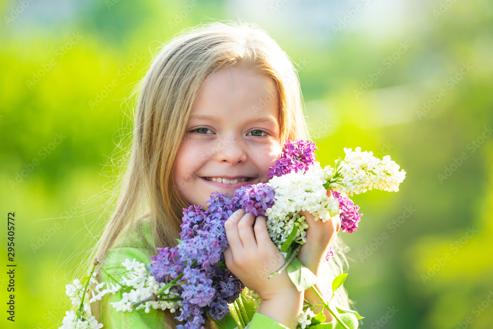 Cheerful young little lady in the garden with long fair hair being excited to get a bouquet of lilac on women's day. Cheerful young little lady in the garden with long fair hair being excited to get a bouquet of lilac on women's day.