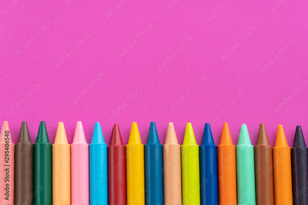 Back to school, minimalism concept. School supplies. Wax crayons on trendy purple color paper background. Copy space, flat lay Back to school, minimalism concept. School supplies. Wax crayons on trendy purple color paper background. Copy space, flat lay