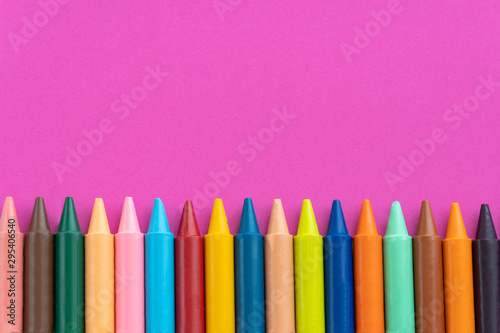 Back to school, minimalism concept. School supplies. Wax crayons on trendy purple color paper background. Copy space, flat lay