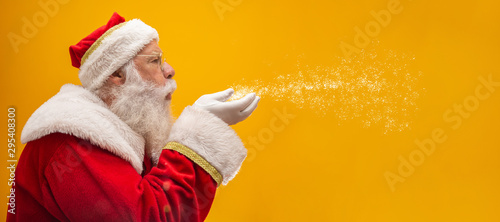 Holly jolly Xmas festive occasion Noel! Christmastime traditions! Santa in headwear, costume, white gloves expresses winter wish, surprise, fantasy, blizzard, snow, snowflakes, air kiss, blowing photo