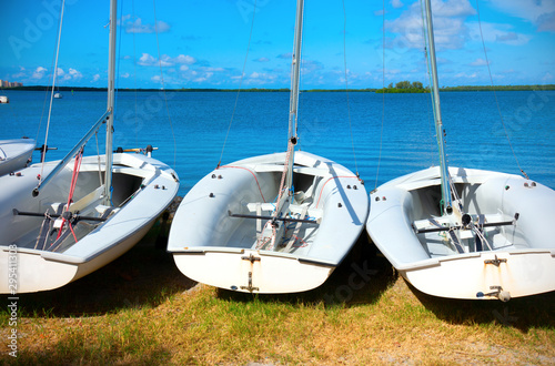 Row of small sailboats lined up along the coast shoreline used for teaching sailing photo