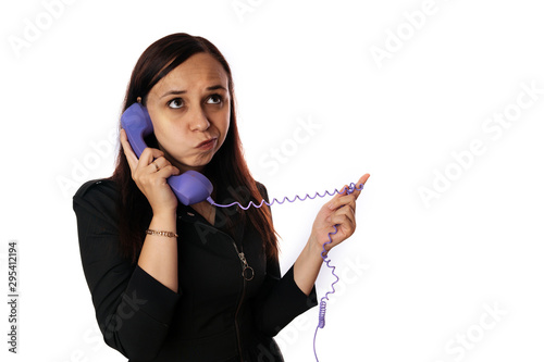 A beautiful young woman in a black dress listens calmly to someone on the home phone on isolated white background. Copy space.