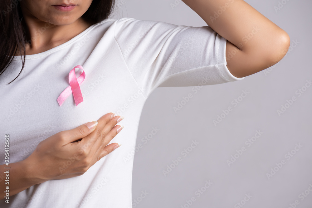 Closeup of pink badge ribbon on woman chest to support breast cancer cause. Healthcare, medicine and breast cancer awareness concept. Closeup of pink badge ribbon on woman chest to support breast cancer cause. Healthcare, medicine and breast cancer awareness concept.