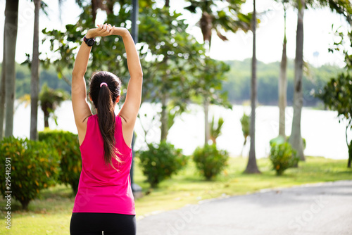 Young fitness woman runner stretching arm before run in the park. Outdoor exercise activities concept.