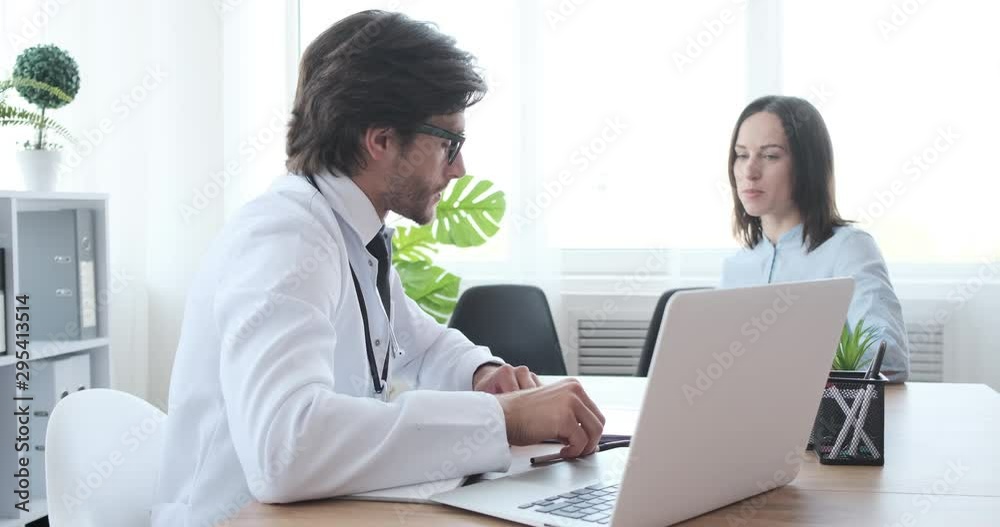 Doctor speaking with woman patient about xray test result at clinic Doctor speaking with woman patient about xray test result at clinic
