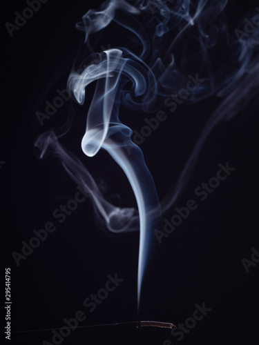 Structure of white smoke, brush effect. Burning incense isolated on black background, close up view. Abstract background of burning sweet smell. Aromatic stick for meditation and relaxation