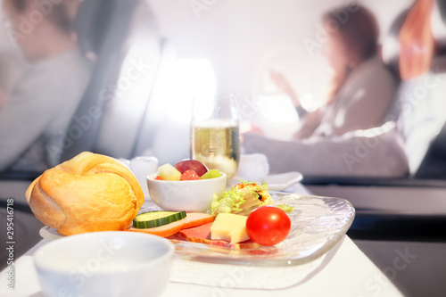 Airplane breakfast food in business class against passenger cabin interior blurred background. Side closeup view of aircraft meal starters on tray table. Luxury jet plane air travel service concept