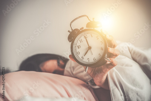 woman lying on the bed hold a clock, late, wake up concept.