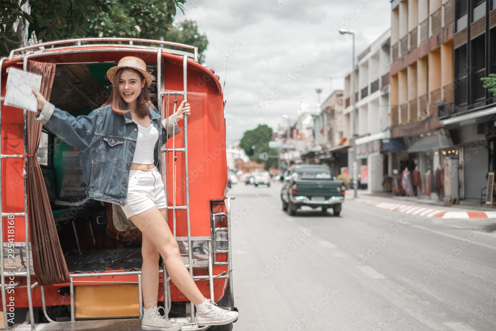 Smiling woman traveler in thapae gate landmark chiangmai thailand standing on the red bus with backpack on holiday, relaxation concept, travel concept