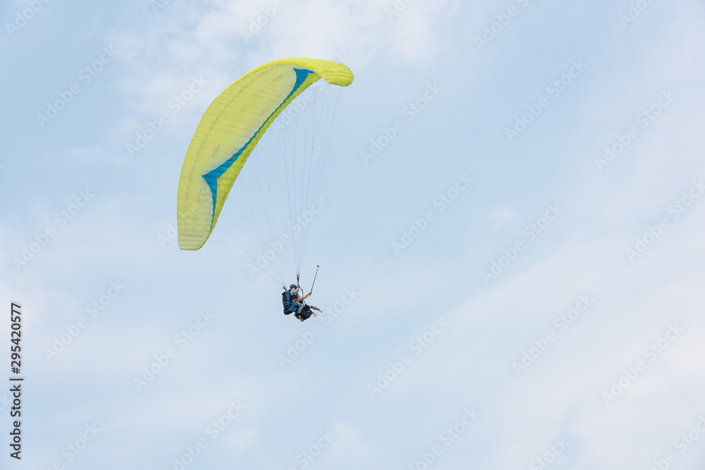 A yellow paraglider flies freely in the blue sky A yellow paraglider flies freely in the blue sky
