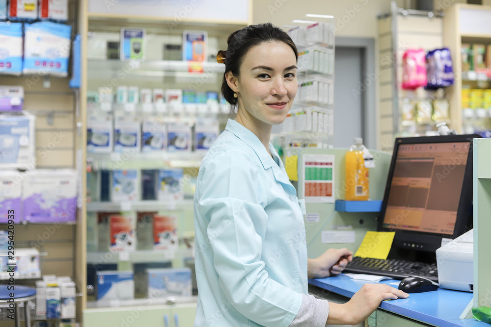 Female pharmacist works in a pharmacy. Pharmacist at the computer in the pharmacy.