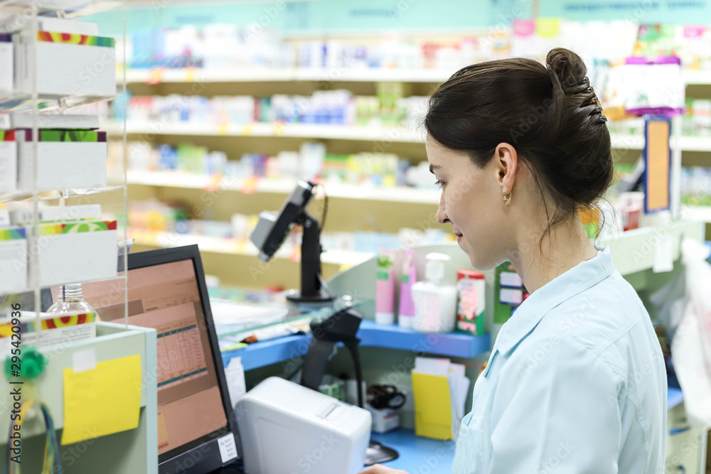 Female pharmacist works in a pharmacy. Pharmacist at the computer in the pharmacy.
