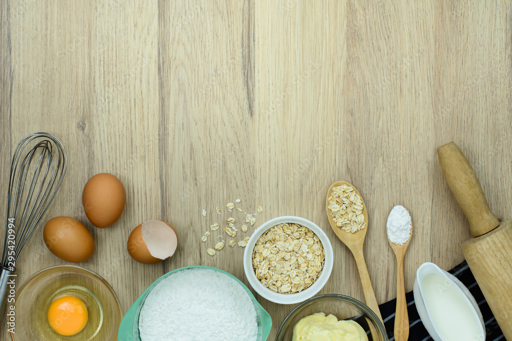 tools and ingredients for baking cake (flour, butter, eggs, milk, Oatmeal) on wooden background. Top view with copy space. tools and ingredients for baking cake (flour, butter, eggs, milk, Oatmeal) on wooden background. Top view with copy space.