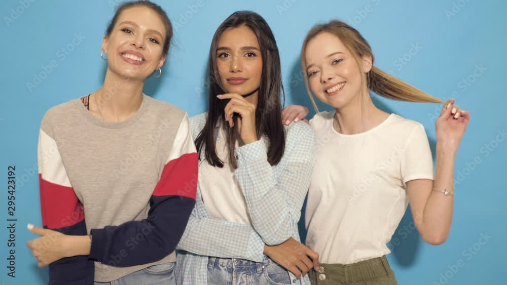 Three young beautiful smiling hipster girls in summer clothes. Sexy carefree women having fun.Positive models going crazy near blue wall in studio. They give air kiss and wink Three young beautiful smiling hipster girls in summer clothes. Sexy carefree women having fun.Positive models going crazy near blue wall in studio. They give air kiss and wink