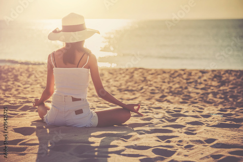 Foto Silhouette woman sitting and doing yoga on the beach