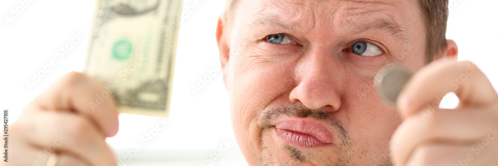 Funny man holding in hands paper and coin currency trying to invent some good solution portrait Funny man holding in hands paper and coin currency trying to invent some good solution portrait