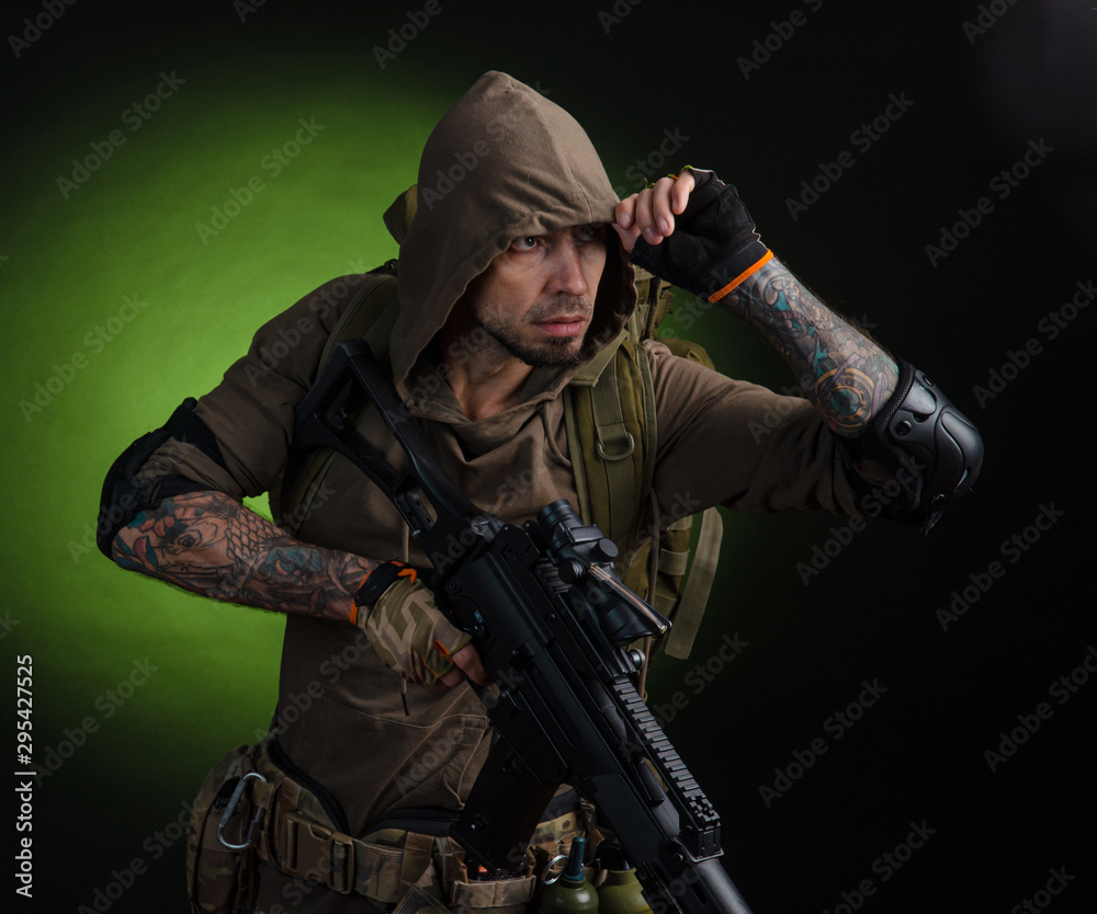 man Stalker with a gun with an optical sight and a backpack on a dark background