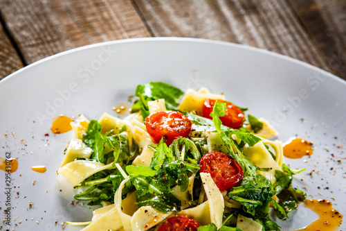 Pasta with tomatoes and arugula on wooden table
