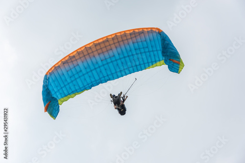  A blue paraglider flies freely in the blue sky