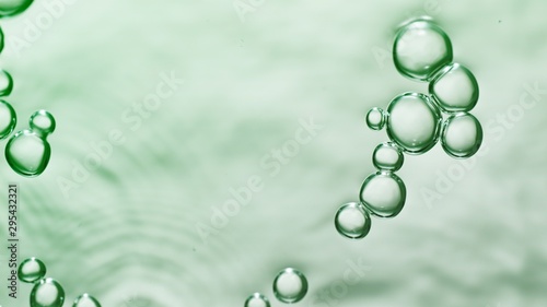 transparent gas bubbles on water surface. Worms-eye low angle with crystal bubbles in purified water on green background. cosmetic backdrop with copy space