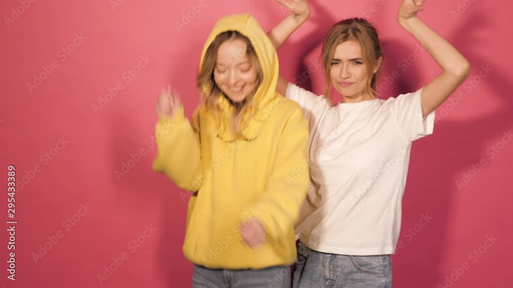 Two young beautiful smiling hipster girls in trendy summer clothes.Sexy carefree women posing in studio near pink wall.Positive models having fun and dance.Showing good relations and hugging Two young beautiful smiling hipster girls in trendy summer clothes.Sexy carefree women posing in studio near pink wall.Positive models having fun and dance.Showing good relations and hugging