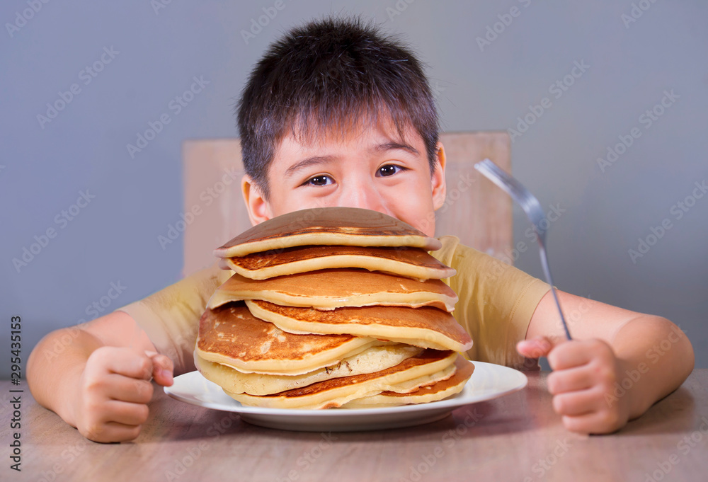 Young boy having pancakes breakfast. 8 years old happy excited child