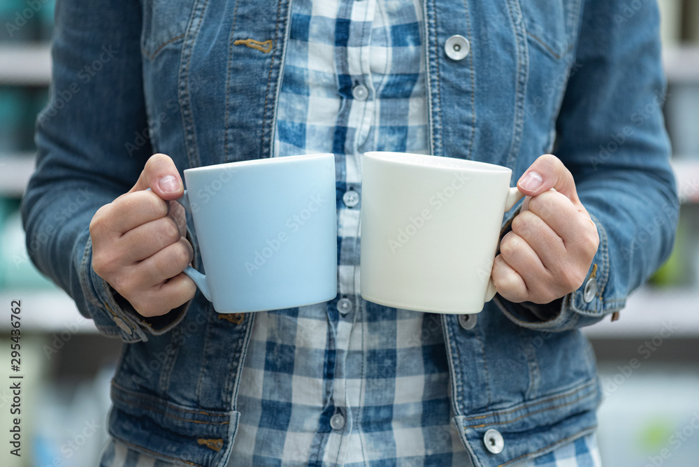 Woman choosing a new ceramic cup for kitchen in a store. Woman choosing a new ceramic cup for kitchen in a store.