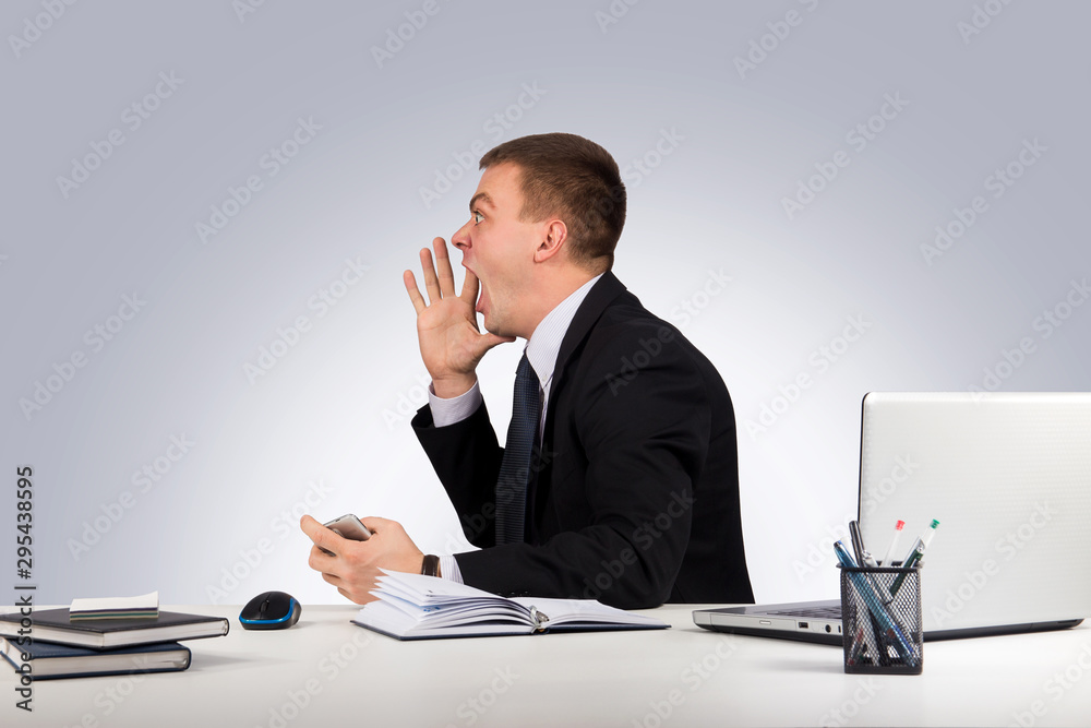 Office, finances, internet, business, success concept-Young man in office shouting with hands cupped to his mouth