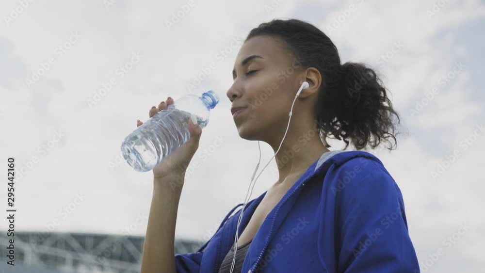 Afro-american runner woman Drinking Water After Running. Portrait Fitness Woman Drinking Water From Bottle. Afro-american runner woman Drinking Water After Running. Portrait Fitness Woman Drinking Water From Bottle.