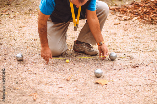 A man plays petanque - checks the distance from the ball to the target ball cochonnet