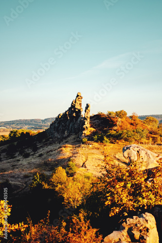 Giant staked sand stone formation in the mountain nature at colorful autumn sunset light. Natural idyllic landscape view. Teufelsmauer, Thale Harz National Park, German Mountains
