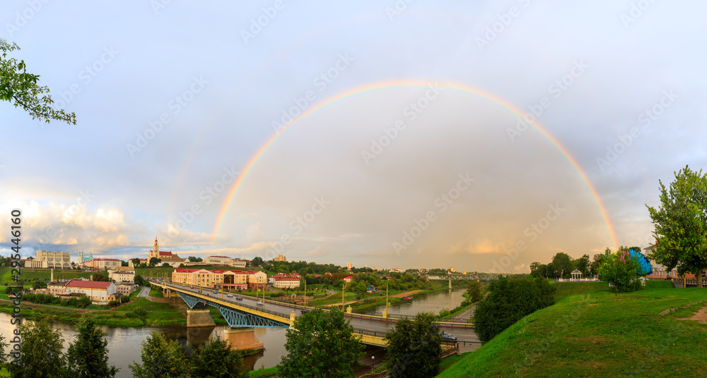 Panoramic view of the city of Grodno, the embankment, the Neman river and the old city. Autumn evening, the city in the sunshine against a background of dark clouds and a rainbow.